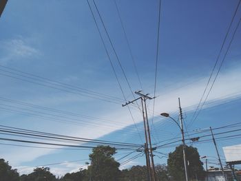 Low angle view of electricity pylon against blue sky