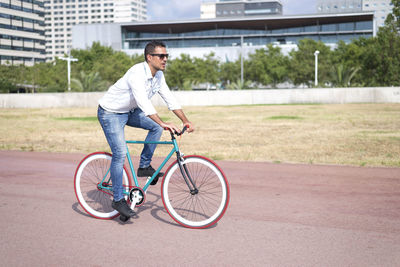 Full length of man riding bicycle on road