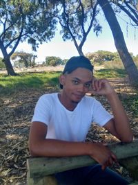 Portrait of young man sitting on field