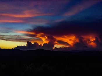 Scenic view of silhouette mountain against dramatic sky at sunset