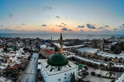 High angle view of city by sea against sky at sunset