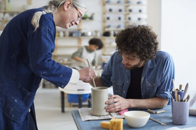 Male and female students learning pottery in class