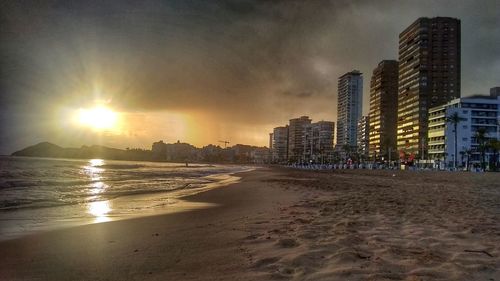 Sea and buildings against sky during sunset