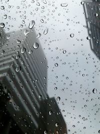 Low angle view of buildings seen through wet glass during monsoon