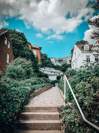 Staircase amidst trees and buildings against sky