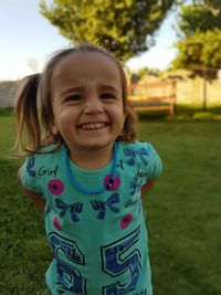 Portrait of smiling girl standing on grassy field