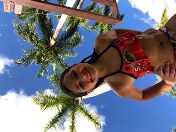 Low angle portrait of smiling woman against sky