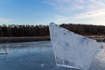 Frozen lake by snowcapped mountain against sky