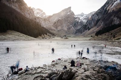 People at frozen lake against mountains 