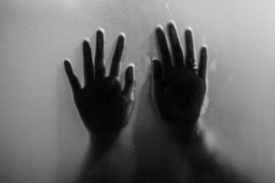 Close-up of hands touching window