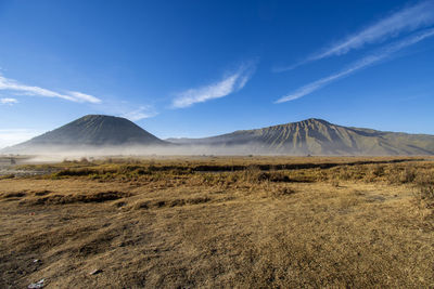 Scenic view of landscape and mountains against blue sky