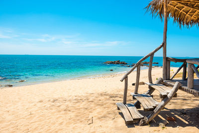 Deck chairs on beach against sky