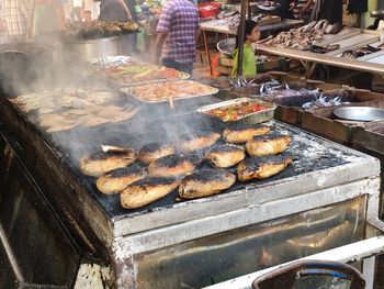 Fishes cooking on barbecue grill in fish market