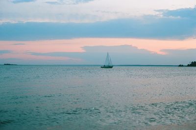 Sailboat sailing on sea against sky during sunset