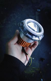 Close-up of man holding lighting equipment on black background