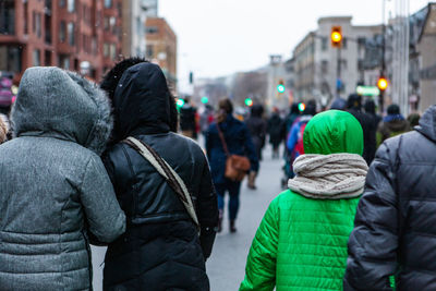 Rear view of people walking on street in city