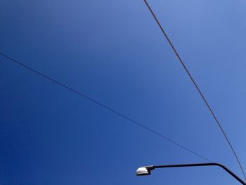 Low angle view of power lines against clear blue sky