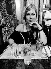 Portrait of woman drinking glass on table at restaurant