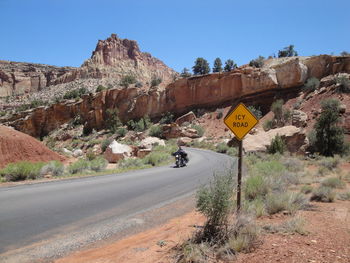 Road by rocky mountains against clear sky