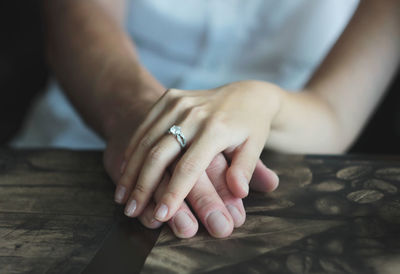 Cropped image of couple holding hands on wooden table