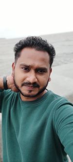 Portrait of young man standing against sea