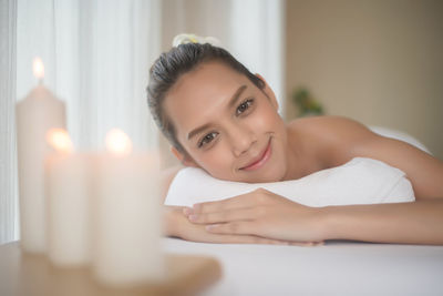 Portrait of young woman lying on massage table in spa