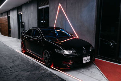 Cars on street against illuminated buildings in city