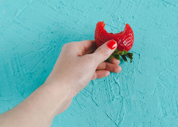 Midsection of person holding strawberry against wall