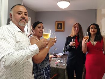 Happy friends drinking glass on table at home