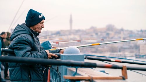 Side view of man standing on railing in city