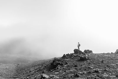 Low angle view of man standing on rock against sky