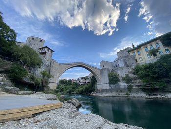 Arch bridge over river against sky