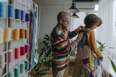 Fashion designer trying patchwork dress on colleague in workshop