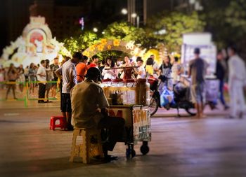 Rear view of people sitting on street in city