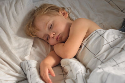 High angle view of cute baby sleeping on bed at home