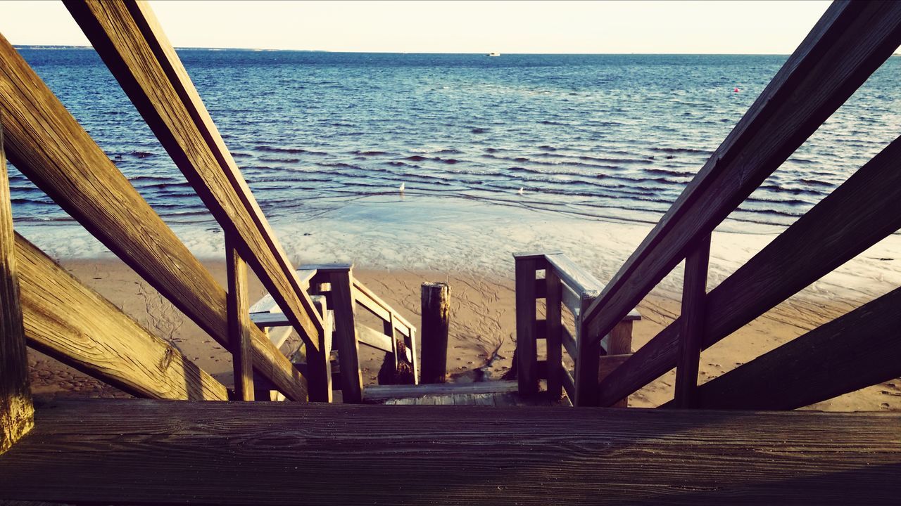 sea, water, railing, horizon over water, pier, wood - material, tranquility, the way forward, tranquil scene, scenics, built structure, nature, jetty, high angle view, boardwalk, beauty in nature, sunlight, ocean, sky, wood