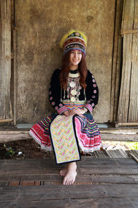 Smiling woman in traditional clothing looking away against wall