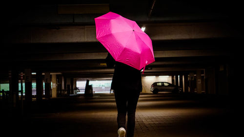 Low section of woman standing on pink umbrella