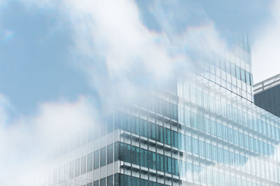 Low angle view of modern building against cloudy sky