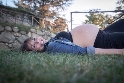 Portrait of pregnant woman lying on field