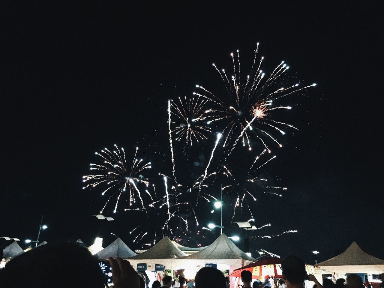 night, firework display, celebration, firework - man made object, event, exploding, long exposure, arts culture and entertainment, motion, low angle view, blurred motion, illuminated, outdoors, firework, real people, sky, large group of people, multi colored, clear sky, people