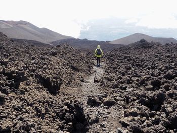 Rear view of man walking on etna volcano mountain