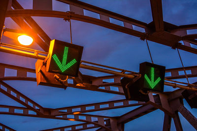 Low angle view of illuminated information sign against sky