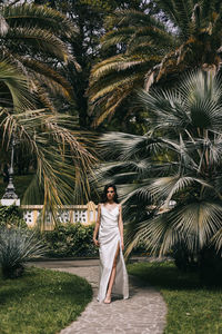 Full length of woman standing by palm tree