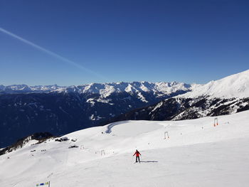 People skiing on snowcapped mountain against clear sky