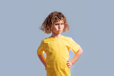 Boy looking away while standing against blue background