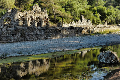 Stone wall with reflection of trees in lake