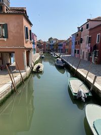 Canal amidst buildings against clear sky in burano