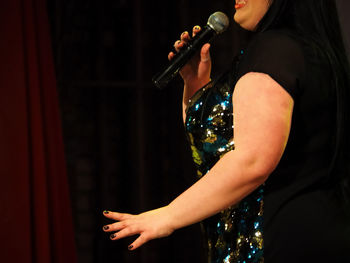 Midsection of woman singing on stage