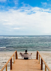 Rear view of man sitting on beach